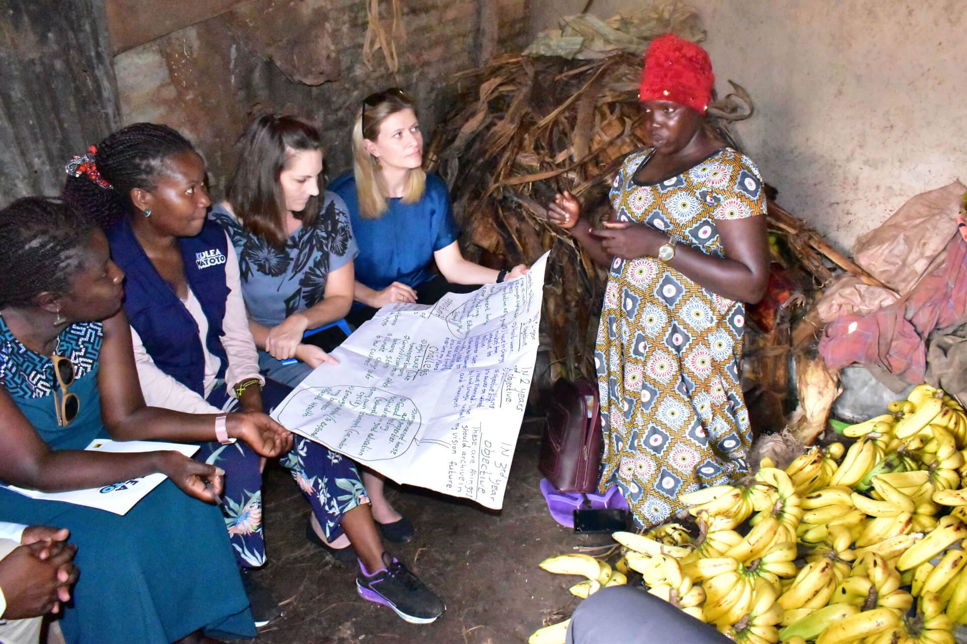 Alice Guwo, a client under the Kulea Watoto shares her vision with IRC staff at her banana store in Makindye during a field visit.