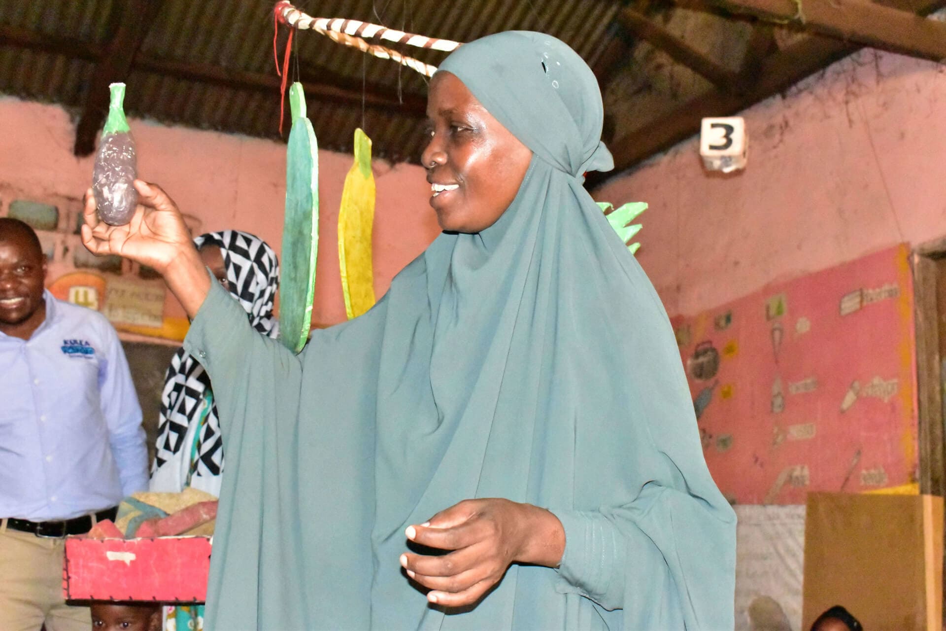 Halima, a caregiver at Kiti ECD and Nursery School displays locally made play items that are being utilized by the ECD as play materials for children.