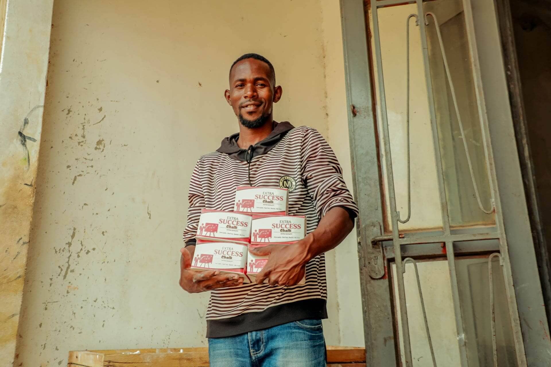 Francis Banda, a client under the Kulea Watoto Project, displays boxes of chalk ready for hit the market. Francis is grateful to the project for the skills in financial management and nurturing children that have made him a better father and businessman