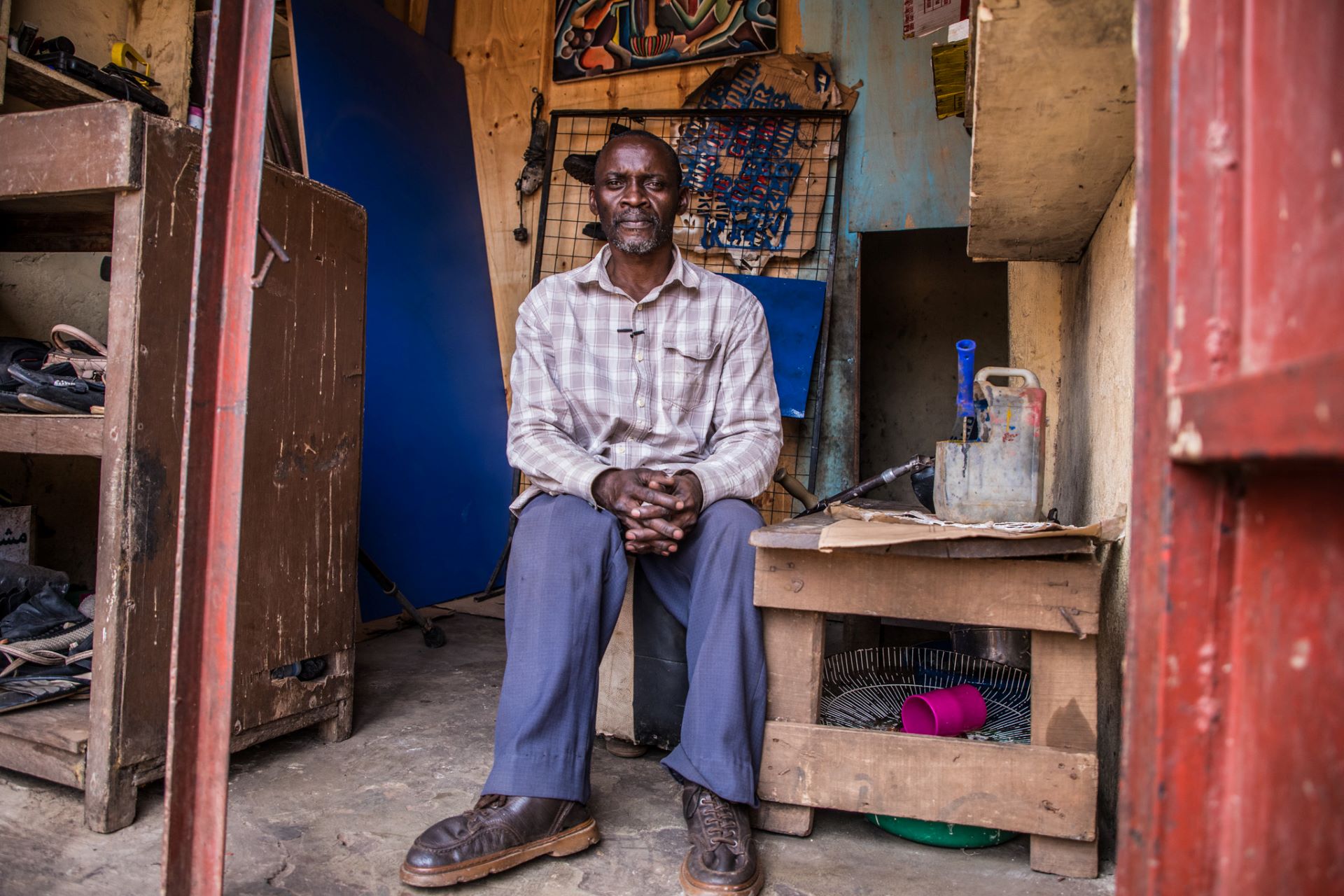 Lawrence sits in his signage workshop. Because of his disability, financial institutions hesitated to offer him financial support until the cash grant he acquired from Kulea Watoto which has supported him rent a shop and expand his business