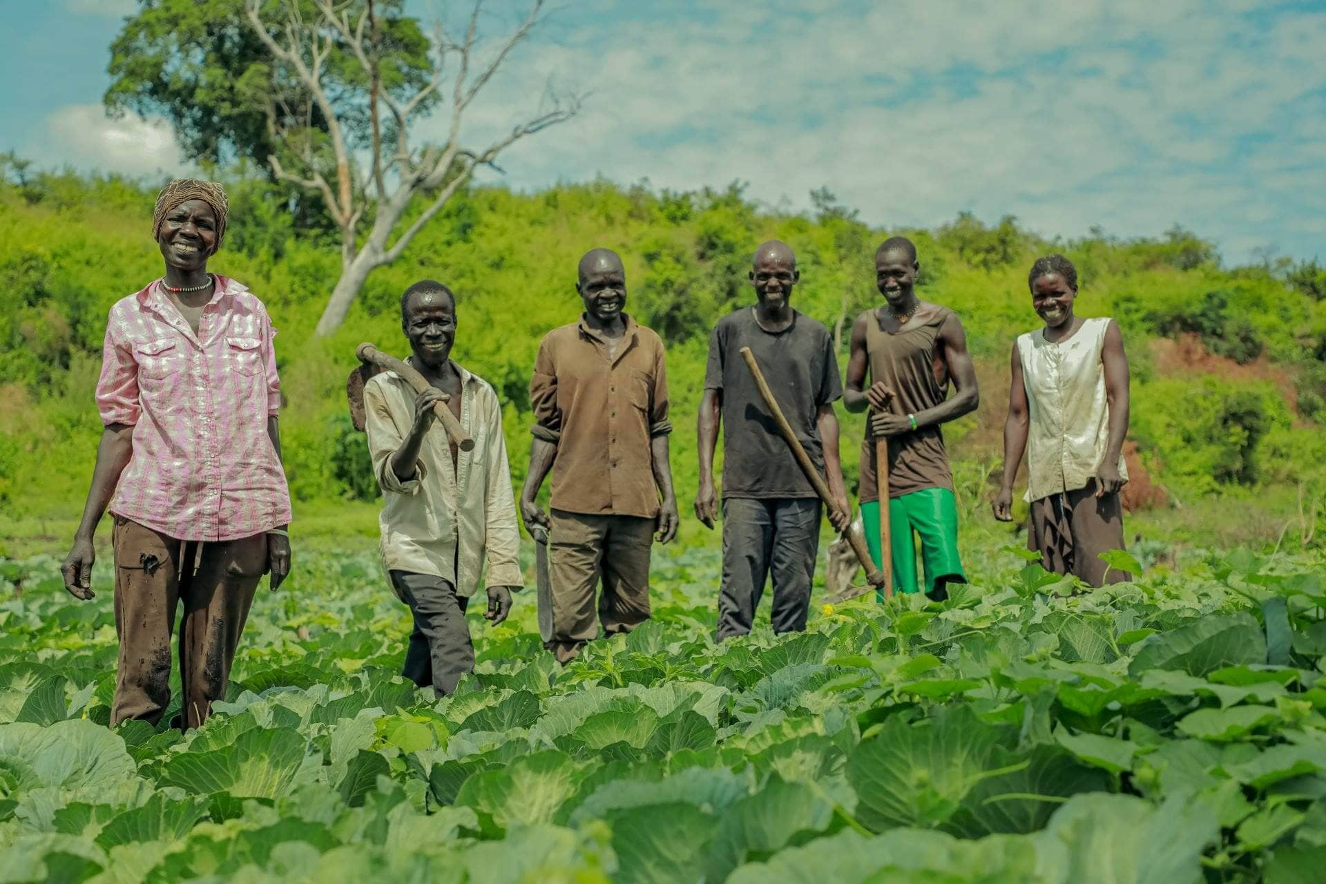 Jafar (third from right) poses for a photograph with members in his farmer group at their garden in Village IV. With proceeds from the garden, the group has been able to support themselves and provide for their families’ basic needs