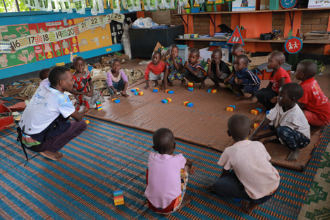 Benon Gumisiriza a caregiver at Lucky Early Childhood Development Center attends to children during class