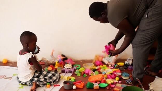 Christine Opina, a lead parent attending to a child at play-space supported by the Kulea Watoto Project in Konge, Makindye Division
