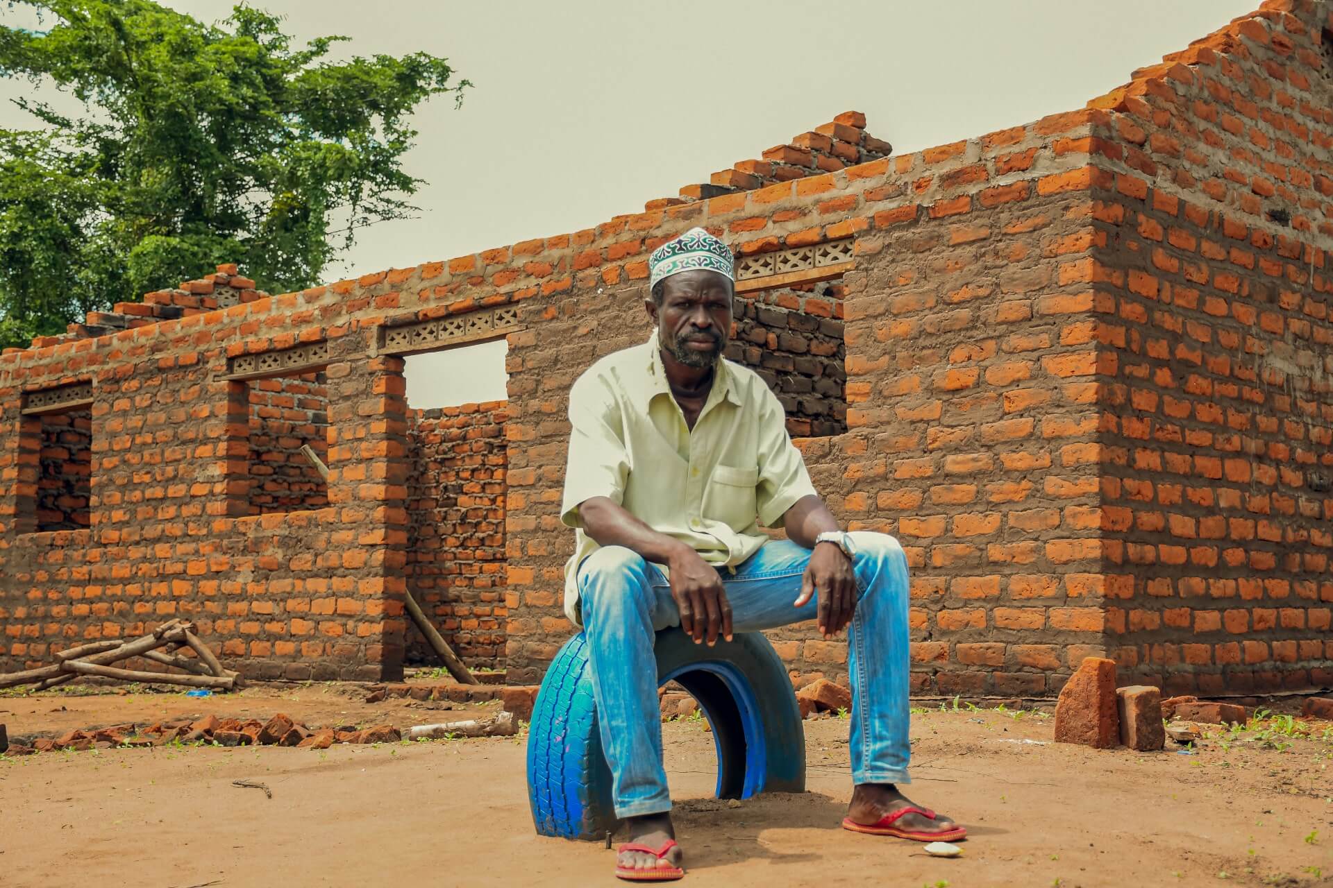 Salim Waiga sits in front of the school structure that has been built thanks to support from parents. He credits the unity in the community to the home learning center which is keeping parents together.