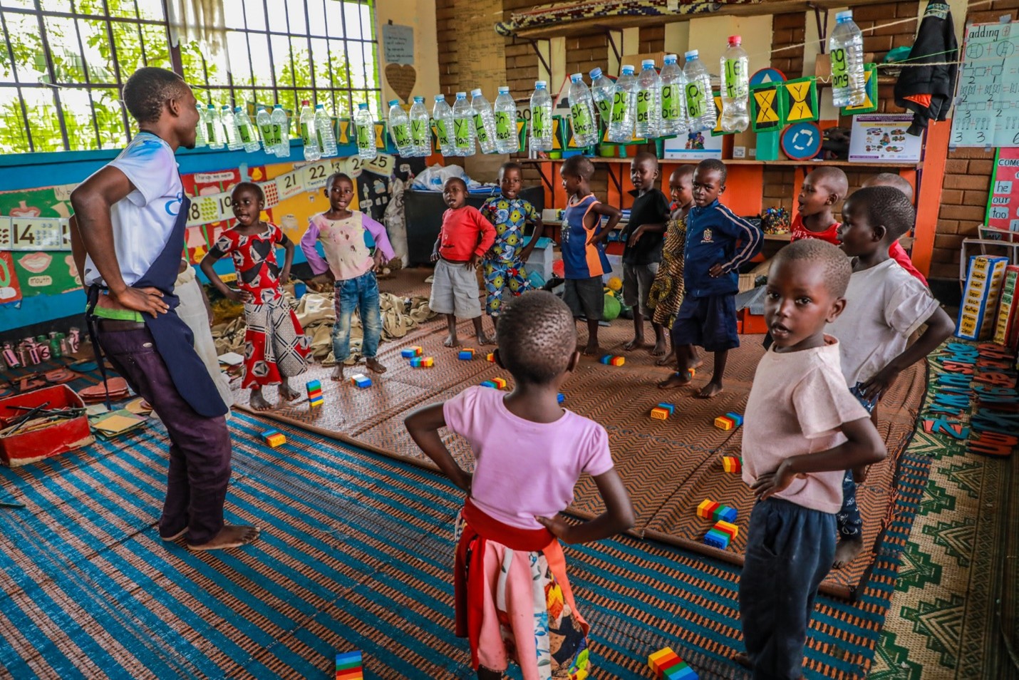 Happy times! Benon engages in a dance with his class. His fellow caregivers are happy with the impact that he is having on the young learners with many confiding when challenged