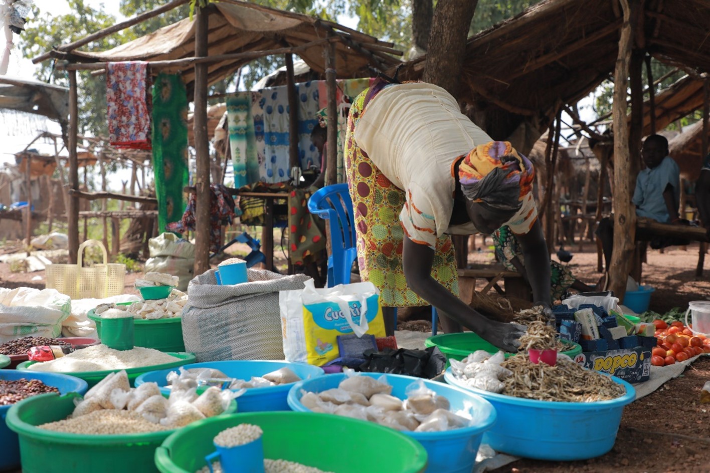 Rose Poni measures up a cup-full of mukene (silver fish) to sell to a customer. From the trainings attained, Rose is able to save up enough money to ensure that her business is sustainable